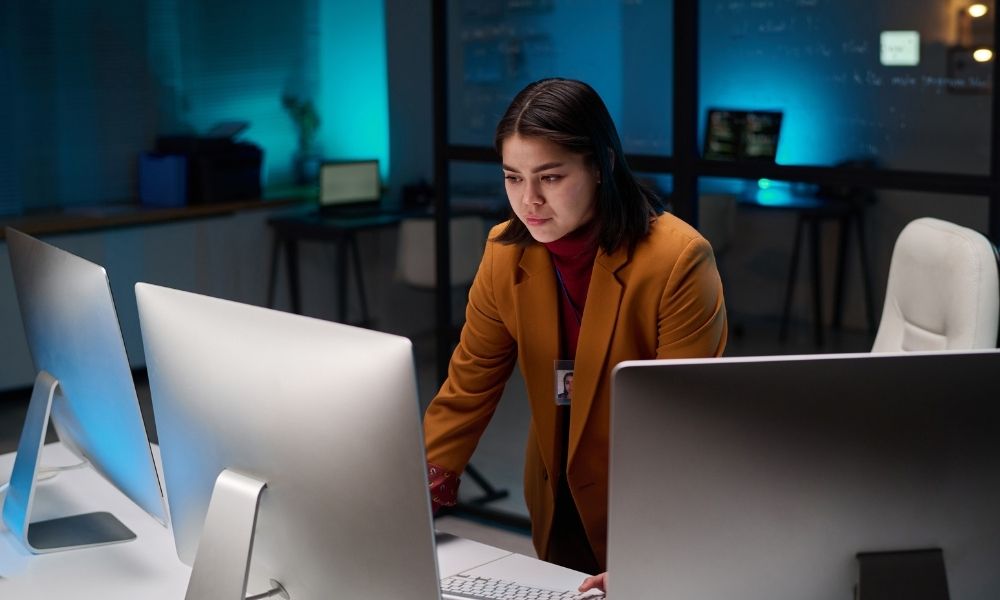 Cybersecurity analyst working at multiple computer monitors in modern office