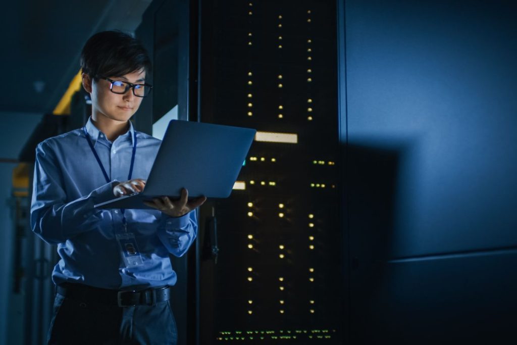 IT professional working on laptop in data center