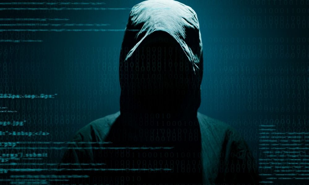 Anonymous hacker silhouette with cybersecurity code overlay